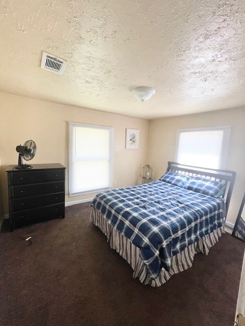 carpeted bedroom featuring visible vents, a textured ceiling, and baseboards