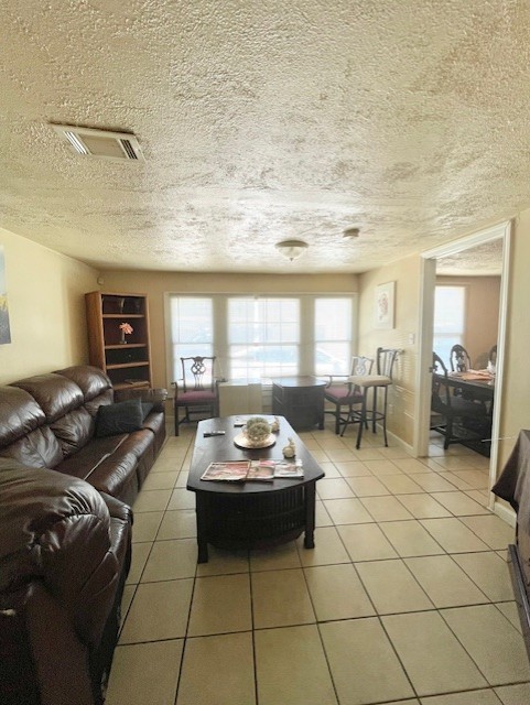 living room with light tile patterned floors, visible vents, and a textured ceiling