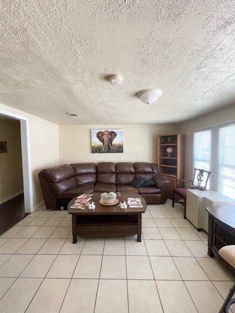 living room featuring a textured ceiling, light tile patterned floors, and visible vents