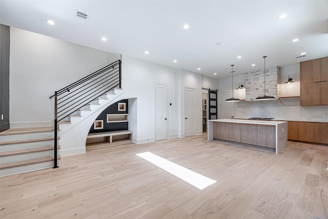 kitchen with a barn door, visible vents, modern cabinets, and brown cabinetry