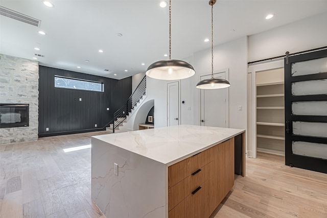 kitchen with light wood-style flooring, modern cabinets, visible vents, and a barn door