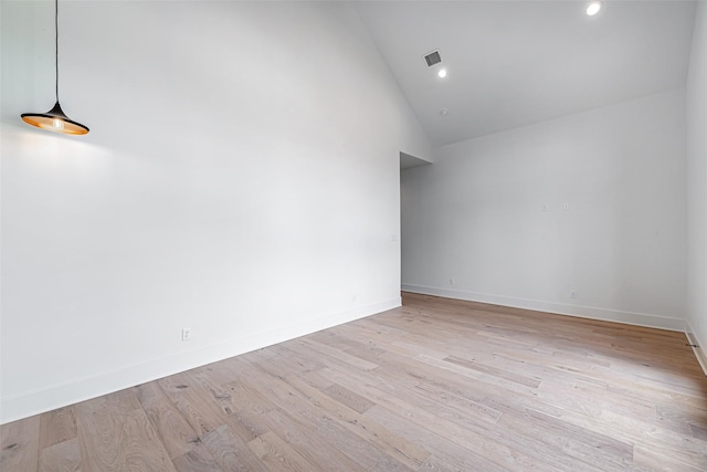 spare room with high vaulted ceiling, visible vents, baseboards, and light wood-style flooring
