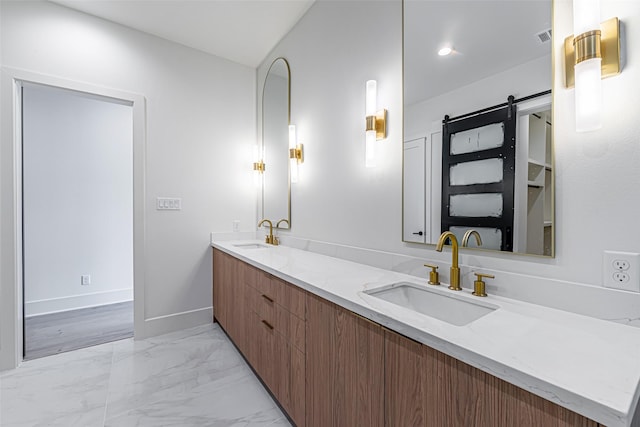 full bath with baseboards, double vanity, marble finish floor, and a sink