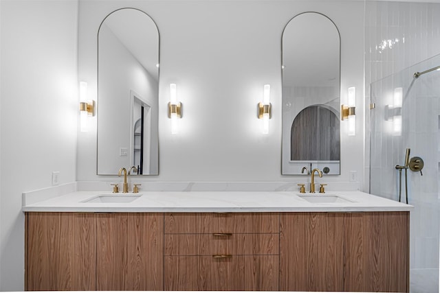 bathroom featuring a shower, double vanity, and a sink