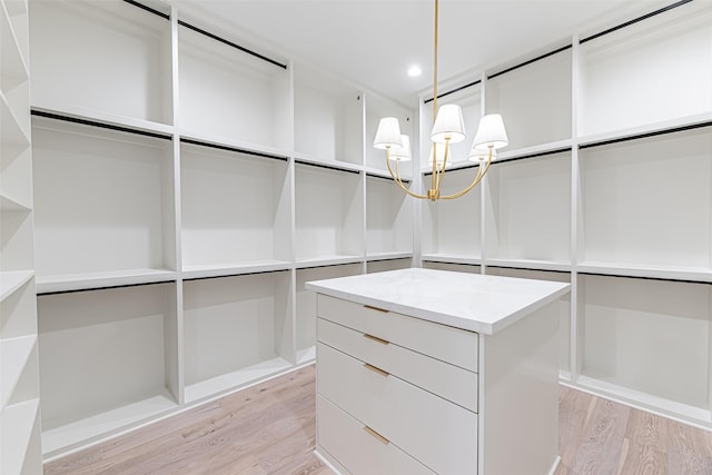 walk in closet featuring light wood-style floors and an inviting chandelier
