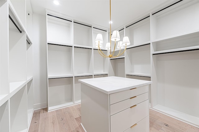 walk in closet with light wood finished floors and a notable chandelier