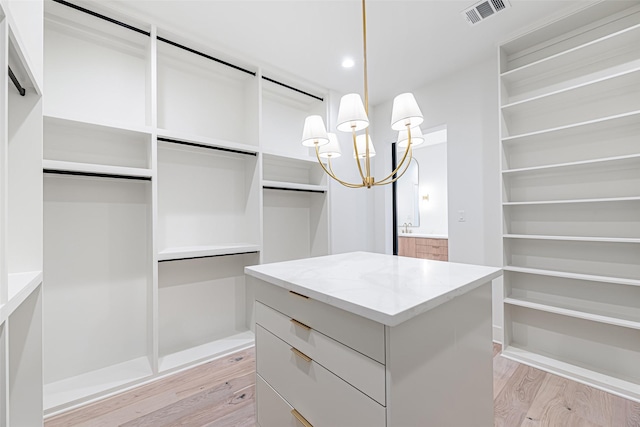 spacious closet with a chandelier, visible vents, and light wood-style flooring