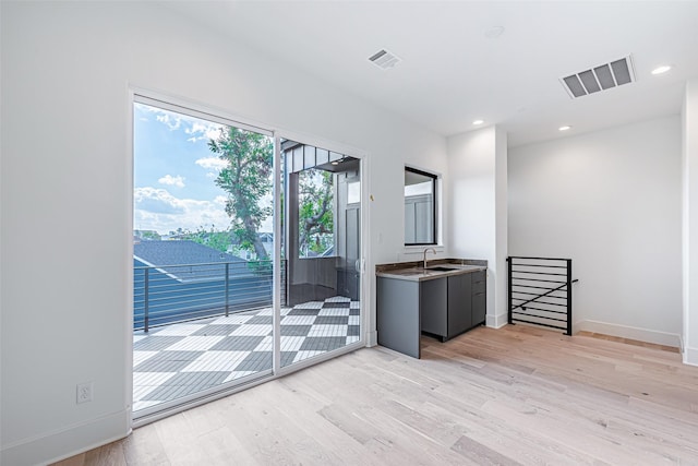spare room with baseboards, light wood-type flooring, recessed lighting, visible vents, and a sink