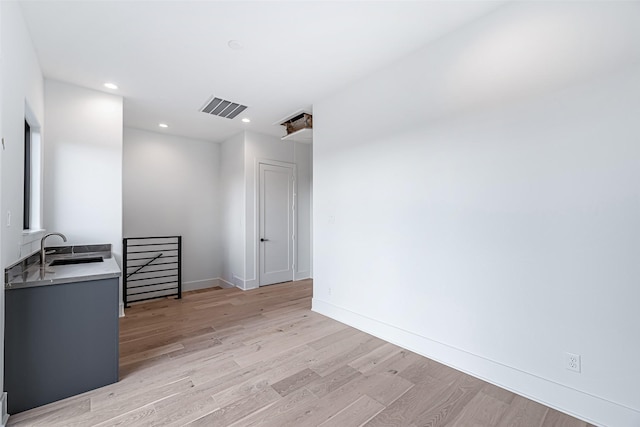 unfurnished room with light wood-style floors, recessed lighting, visible vents, and a sink