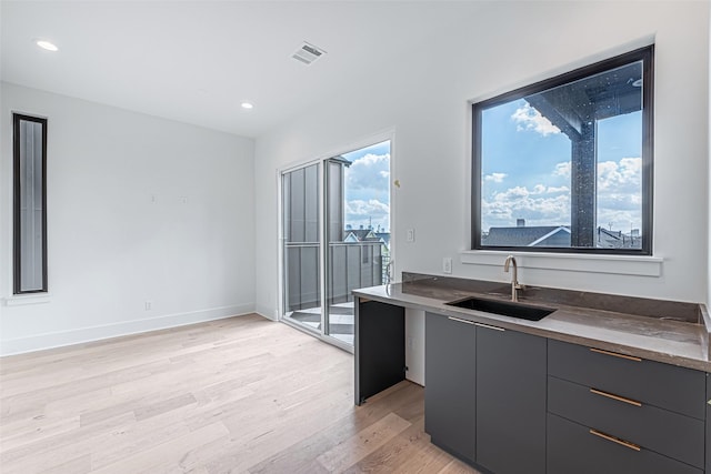 kitchen with light wood-style flooring, a sink, modern cabinets, and visible vents