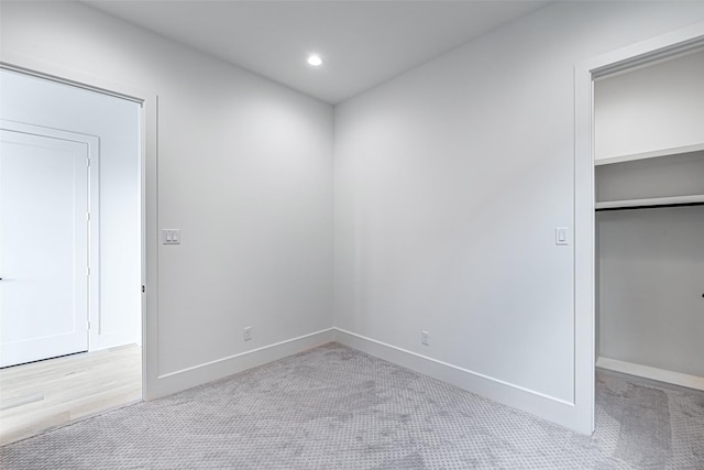 unfurnished bedroom featuring a closet, baseboards, a walk in closet, and carpet floors