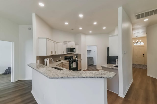 21320 Heritage Forest Ln, Porter, TX 77365 - kitchen featuring black range with gas stovetop, stainless steel microwave, a sink, dark wood-style floors, and light stone counters