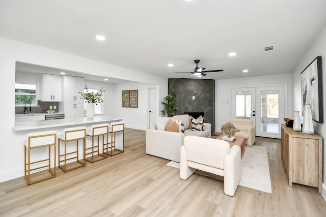 living room featuring light wood-style flooring, ceiling fan, visible vents, and recessed lighting