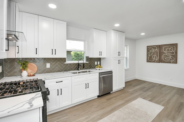 kitchen with light stone counters, white cabinetry, backsplash, stainless steel dishwasher, and a sink
