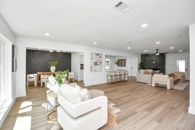 living room featuring light wood-type flooring, baseboards, visible vents, and recessed lighting