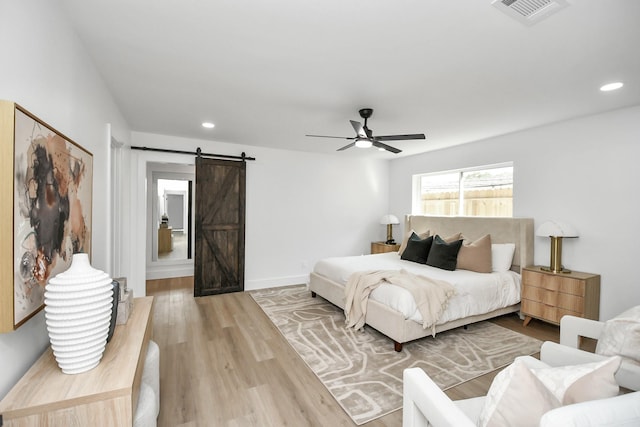 bedroom featuring a ceiling fan, visible vents, recessed lighting, a barn door, and wood finished floors