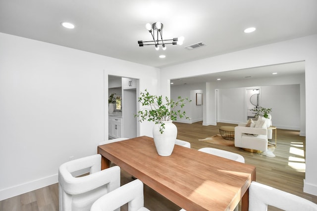 dining space with an inviting chandelier, light wood-type flooring, visible vents, recessed lighting, and baseboards