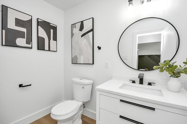 bathroom with toilet, baseboards, vanity, and wood finished floors