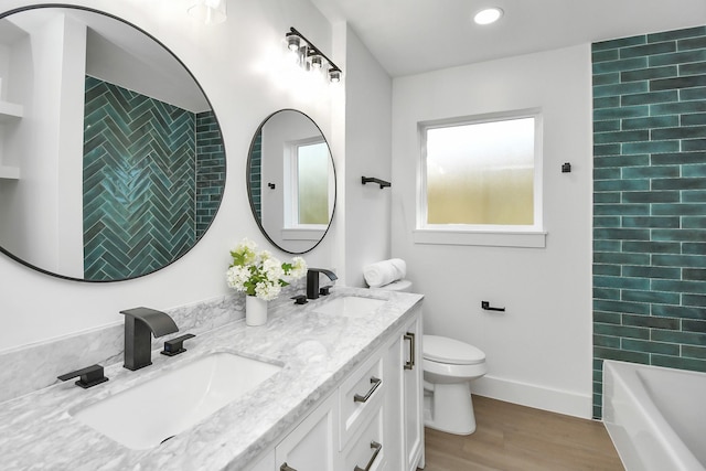 bathroom with toilet, wood finished floors, a sink, and a tub