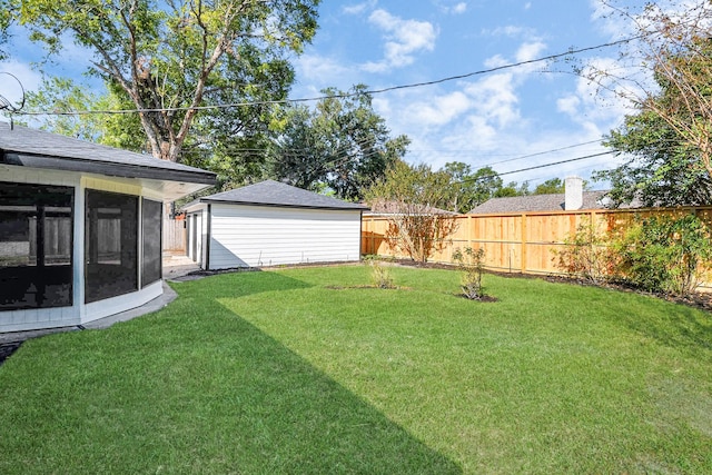 view of yard featuring a fenced backyard, a sunroom, and an outbuilding