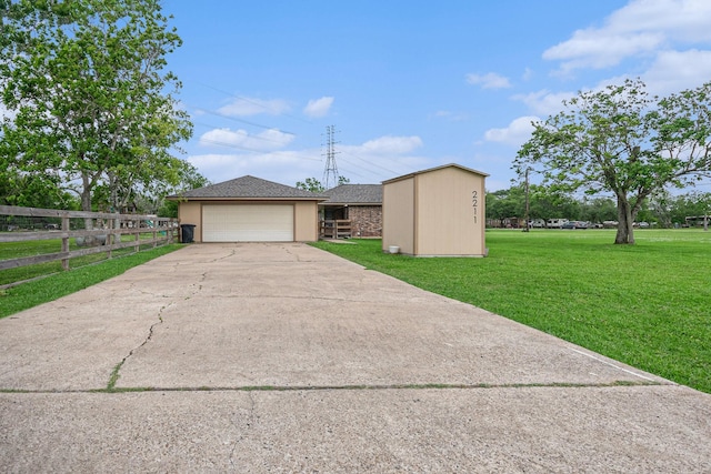 view of front facade featuring an outbuilding, a front lawn, concrete driveway, fence, and stucco siding