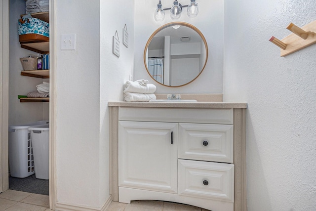 bathroom featuring vanity, a textured wall, and tile patterned flooring