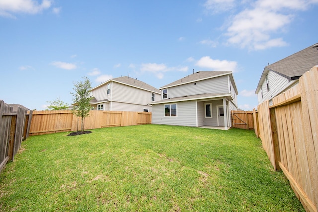 back of property featuring a yard, a patio, and a fenced backyard