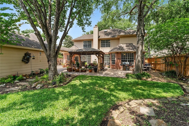 rear view of house featuring a gazebo, a patio area, a chimney, a yard, and brick siding