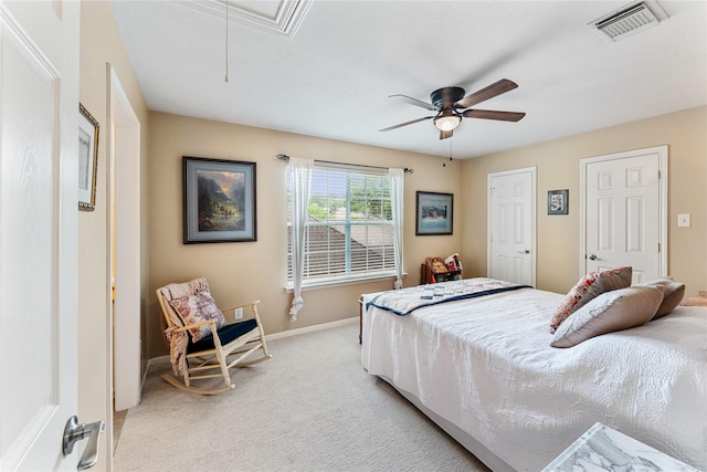 bedroom with light colored carpet, attic access, ceiling fan, baseboards, and visible vents