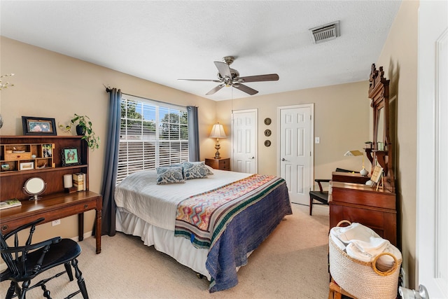 bedroom featuring a ceiling fan, visible vents, and light carpet
