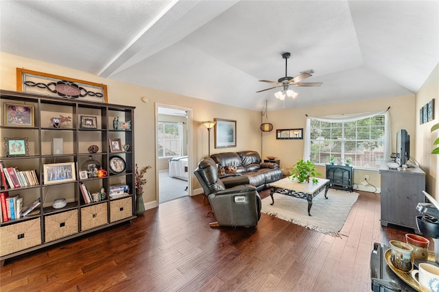 living area with a wealth of natural light, a wood stove, wood finished floors, and a ceiling fan