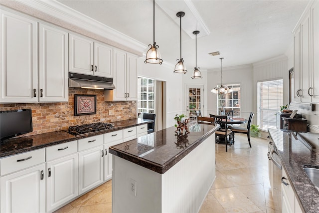 kitchen featuring decorative backsplash, white cabinets, crown molding, under cabinet range hood, and gas stovetop