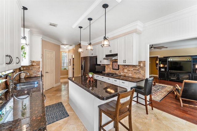 kitchen featuring a sink, visible vents, under cabinet range hood, fridge with ice dispenser, and stainless steel gas cooktop