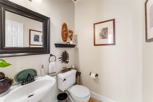 half bathroom featuring toilet, a sink, and baseboards