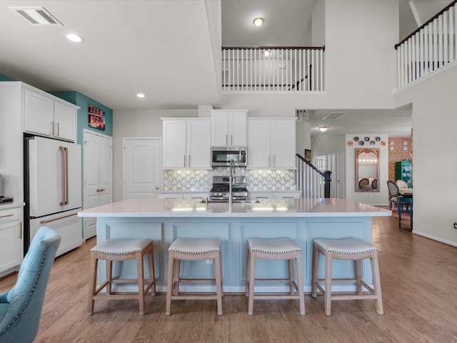1800 Bright Way Ln, Dickinson, TX 77539 - kitchen with stainless steel appliances, light countertops, backsplash, white cabinetry, and light wood finished floors