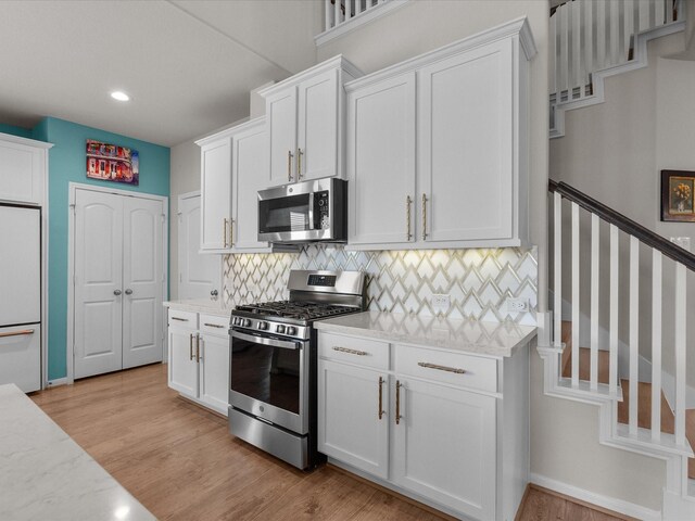 1800 Bright Way Ln, Dickinson, TX 77539 - kitchen with appliances with stainless steel finishes, tasteful backsplash, white cabinetry, light wood-type flooring, and recessed lighting