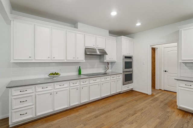 2350 Hewitt St, League City, TX 77573 - kitchen featuring double oven, under cabinet range hood, white cabinetry, black electric cooktop, and tasteful backsplash