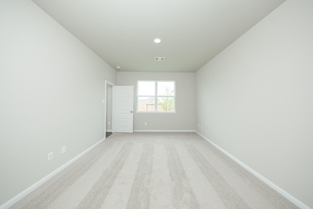 empty room featuring baseboards, visible vents, and light colored carpet