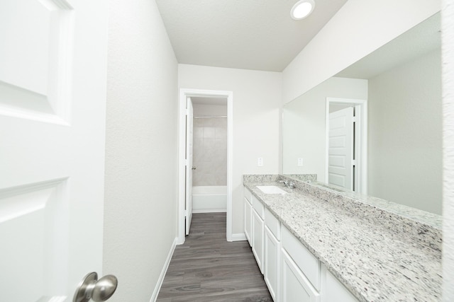 full bathroom featuring baseboards, wood finished floors, and vanity