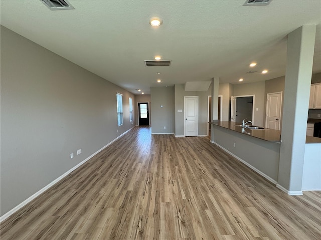 unfurnished living room featuring recessed lighting, visible vents, baseboards, and wood finished floors