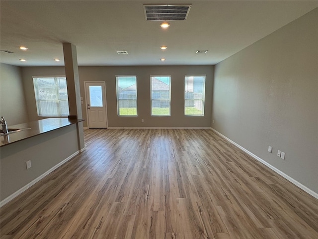 unfurnished living room with wood finished floors, baseboards, and visible vents