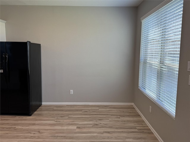unfurnished dining area with a wealth of natural light, light wood-type flooring, and baseboards