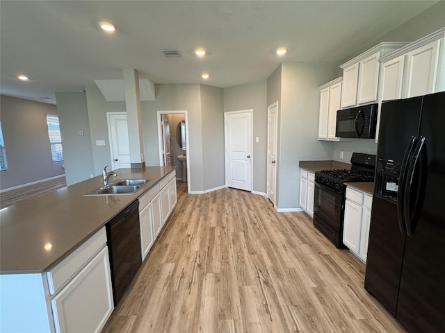 kitchen with an island with sink, light wood-type flooring, white cabinetry, black appliances, and a sink