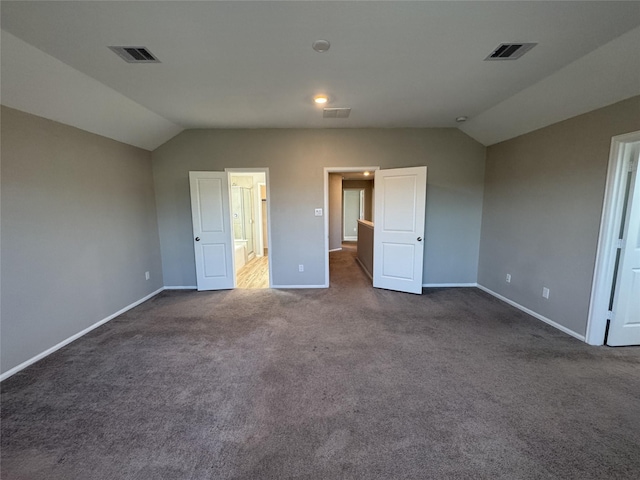 unfurnished bedroom with visible vents, baseboards, dark colored carpet, and vaulted ceiling