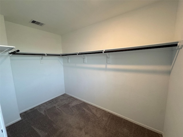 spacious closet featuring dark carpet and visible vents
