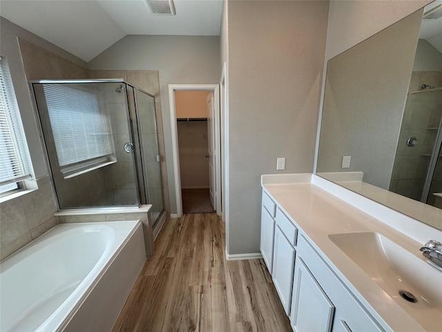 bathroom with visible vents, a bath, a stall shower, and wood finished floors