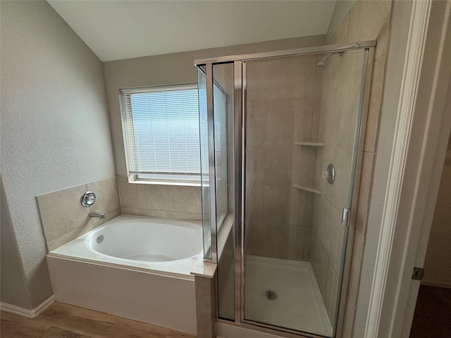 full bathroom with a stall shower, wood finished floors, a textured wall, and a garden tub
