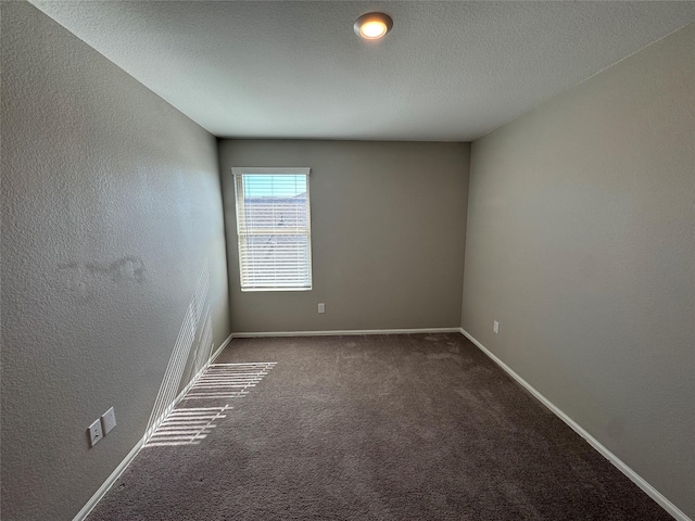 empty room with a textured ceiling, a textured wall, baseboards, and carpet floors