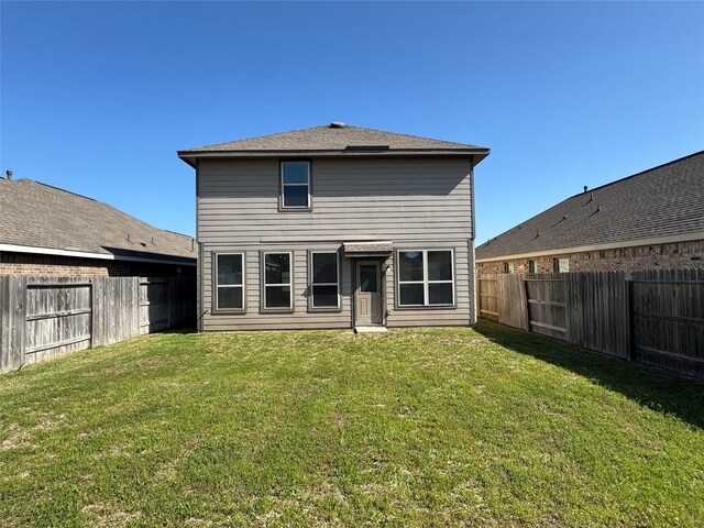 rear view of house featuring a yard and a fenced backyard