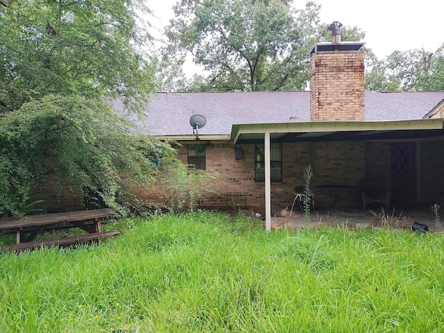 rear view of house featuring roof with shingles and a chimney